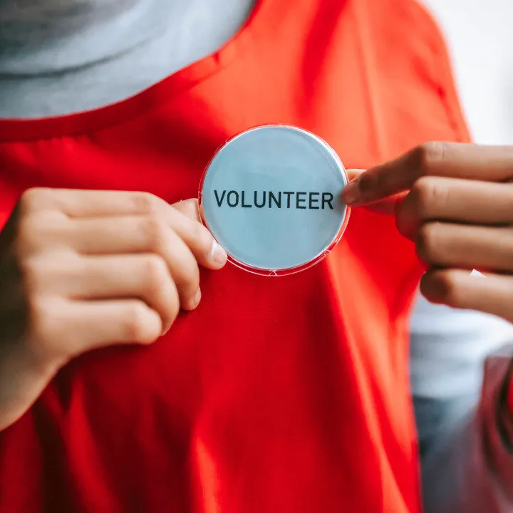 person holding volunteer sign on red apron