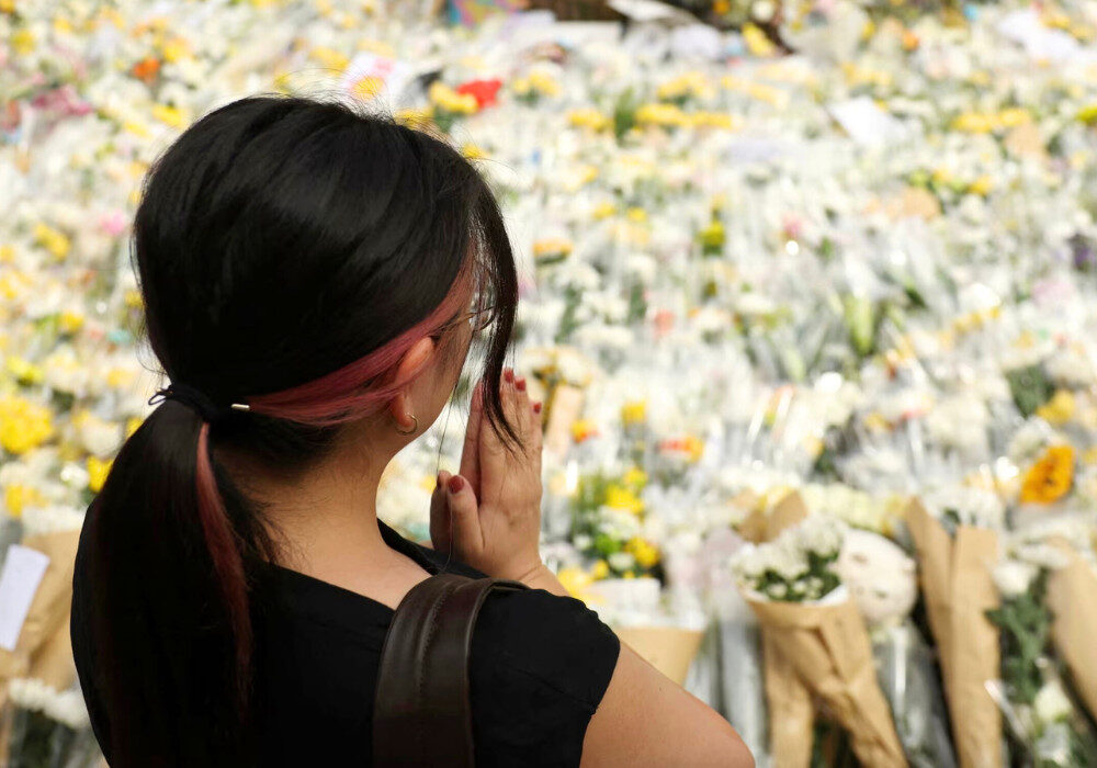 woman praying at tribute for tai po fire victims